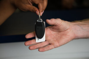 a hand is passing a car rental key to another hand