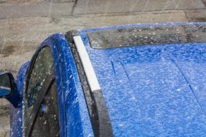 Hail falls on a blue car's roof