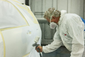 Technician painting a car in a paint room