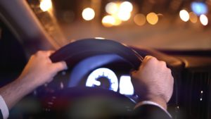 Male Hands On Steering Wheel, Backseat Shot With View On Road At Night