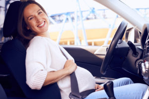 pregnant woman posing on driver seat in car