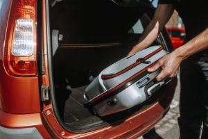 A man putting a luggage in a rental car, driving abroad